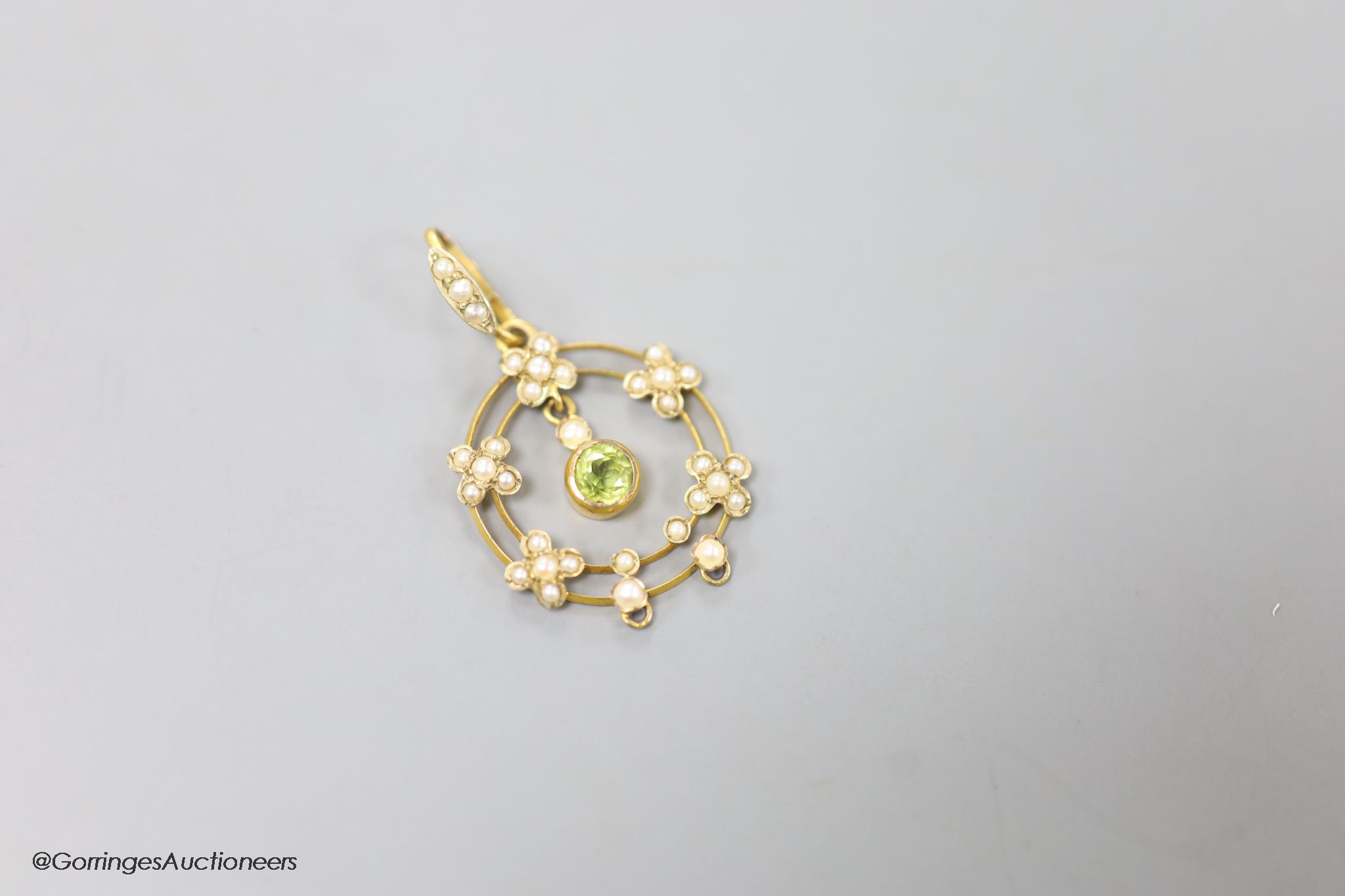 An early 20th century 9ct, peridot and seed pearl set drop pendant, overall 35mm, gross weight 2.1 grams.